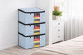 Stack of light blue storage bags with colorful items inside, placed on a wooden floor.
