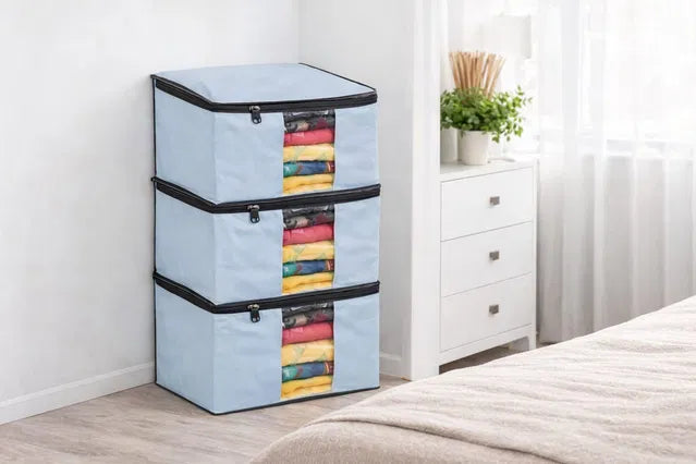 Stack of light blue storage bags with colorful items inside, placed on a wooden floor.